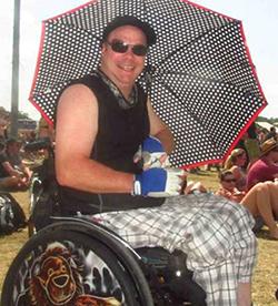 Rollinator Steffen Löw im Rollstuhl ausgestattet mit Sonnenschirm und E.COOLINE Kühlweste