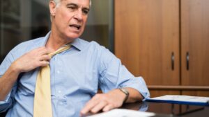 Mann Hitzeproblem im Büro. Versucht, den Kragen zu öffnen